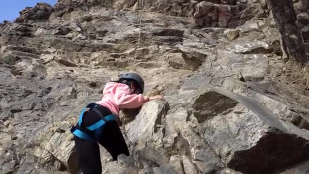 Девушка занимается скалолазанием на крутой скале — стоковое видео