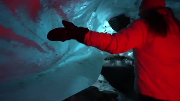 Une fille touche de la glace centenaire dans une grotte de glace. — Video