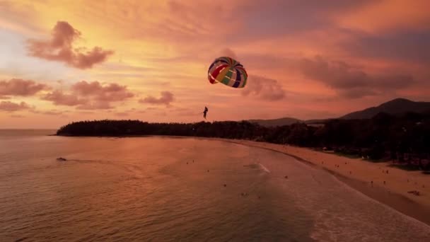 Parasailing bij een oranje zonsondergang op het strand. — Stockvideo