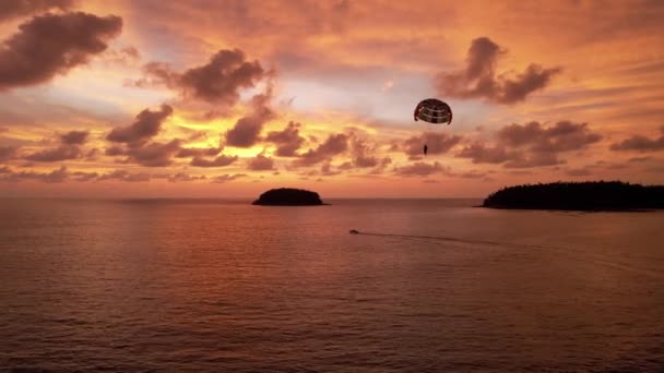 Parasailing bij een oranje zonsondergang op het strand. — Stockvideo