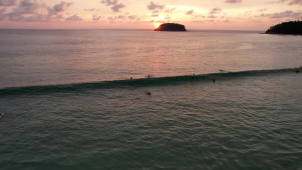 Les surfeurs attrapent les vagues au coucher du soleil. La vue depuis le drone — Video