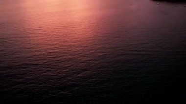 Deniz ve ada manzaralı turuncu gün batımı