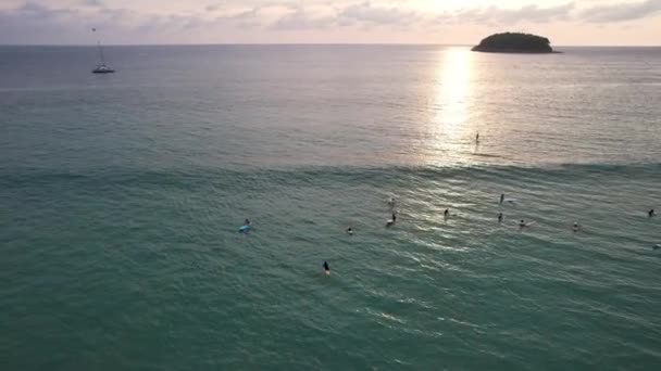 Los surfistas cogen olas al atardecer. La vista desde el dron — Vídeos de Stock