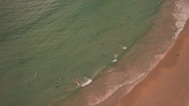 Sörfçüler gün batımında dalga yakalarlar.