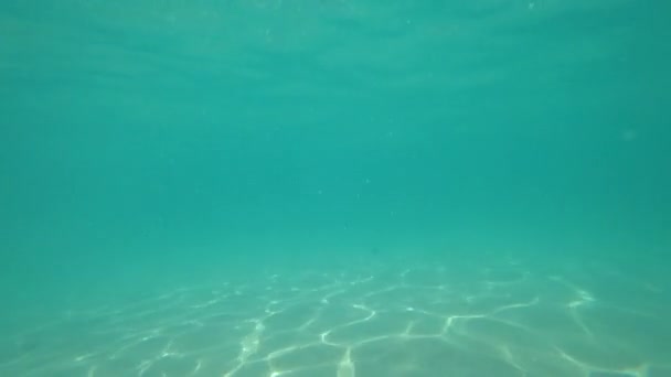 The suns rays shimmer on the sand under the water — Stockvideo