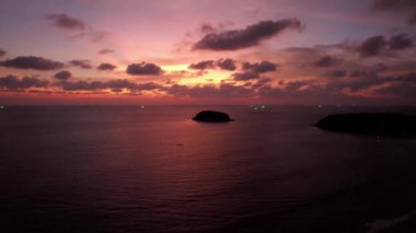 Deniz ve ada manzaralı turuncu gün batımı