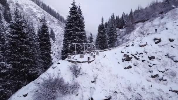Ein kaputter Pavillon steht auf einem schneebedeckten Hügel in den Bergen — Stockvideo