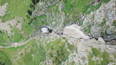 Dik dağ kayalıkları ve bir buz mağarası manzarası..