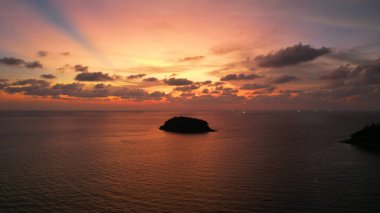 Deniz ve ada manzaralı turuncu gün batımı
