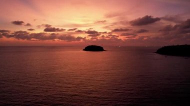 Deniz ve ada manzaralı turuncu gün batımı