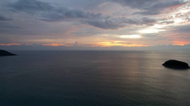 Kırmızı-turuncu gün batımı denizdeki bulutlarla yansıtılır. Uzaktan bir ada görülebilir. Pürüzsüz su ayna gibidir. Issız bir ada var. Balıkçı teknelerinin yeşil ışıkları parlıyor