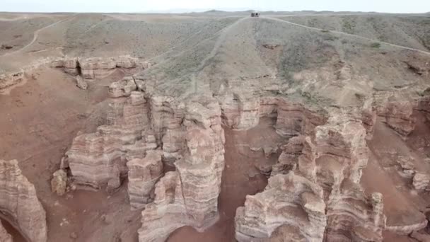 大峡谷沙林 沉积岩中的岩石 岩石上有巨大的裂缝 地面是红色的橙色 从无人机上俯瞰 中间有一条路 不同颜色的土层 — 图库视频影像