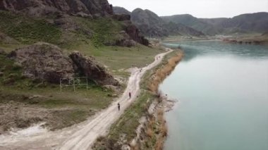 Geniş Nehir ILI. İnsanlar nehir boyunca koşup spor yapıyorlar. İHA 'nın üst görüntüsü. Su yeşil tepeleri, gökyüzünü ve otları yansıtıyordu. Doğada yolda koşmak. Kazakistan.
