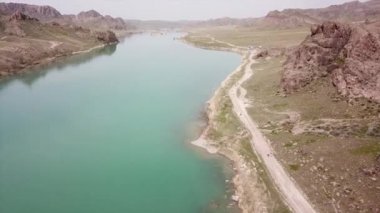 Geniş Nehir ILI. İnsanlar nehir boyunca koşup spor yapıyorlar. İHA 'nın üst görüntüsü. Su yeşil tepeleri, gökyüzünü ve otları yansıtıyordu. Doğada yolda koşmak. Kazakistan.