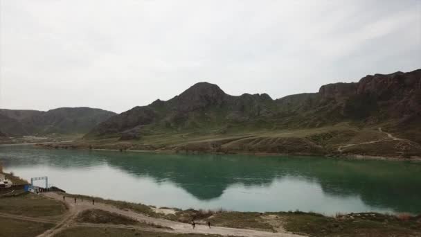 宽的Ili河 人们沿河跑步和运动 从无人机上俯瞰 水反映了青山 天空和草地 在大自然的道路上奔跑 哈萨克斯坦 — 图库视频影像