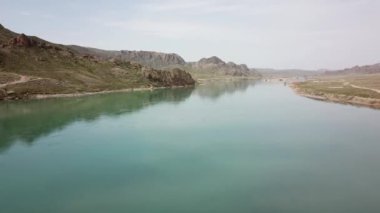 Geniş Nehir ILI. İnsanlar nehir boyunca koşup spor yapıyorlar. İHA 'nın üst görüntüsü. Su yeşil tepeleri, gökyüzünü ve otları yansıtıyordu. Doğada yolda koşmak. Kazakistan.