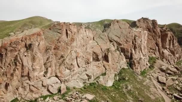 男が岩に登る アクティブなレクリエーションやスポーツ 装備を持った登山 極端な野外活動 カザフスタンのタンガリータスの高い岩 無人機からの眺め 緑の草 — ストック動画