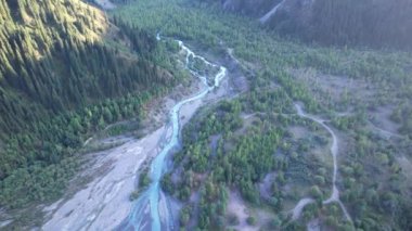 Yüksek bir yerden Issyk Dağı manzarası. Buzuldaki turkuaz-zümrüt suyu. Dağların, ormanların ve suyun üzerindeki güneşin yansıması. Nehir göle akar. Issyk Barajı. Kazakistan
