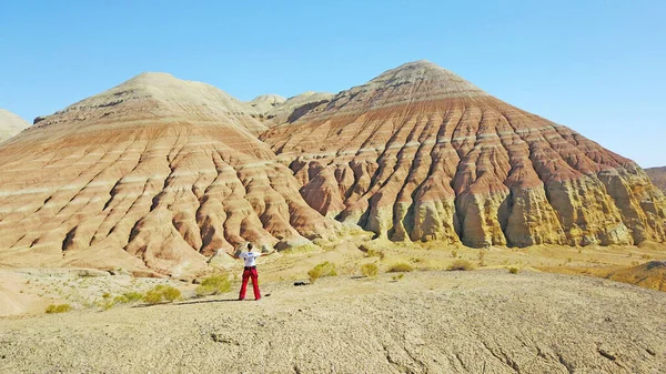 Meditation among the colored mountains. Limestone mountains in the middle of the desert. Colored hills from white to red. The guy sits and contemplates the nature of the Altyn Emel canyon. Kazakhstan.