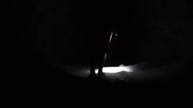 Karanlık bir mağarada fenerli bir adam. Karanlık bir dağ tünelinde el feneri ve sırtında bir sırt çantasıyla yürümek. Mağaranın taş duvarları bir fenerle aydınlatılır. Tehlikeli bir yer..
