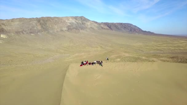 哈萨克斯坦的巨大沙丘 在一个歌唱的沙丘上从无人机上俯瞰 一群人正在山顶上休息 很多黄色的沙子 可以看到人的痕迹 蓝天乌云 — 图库视频影像