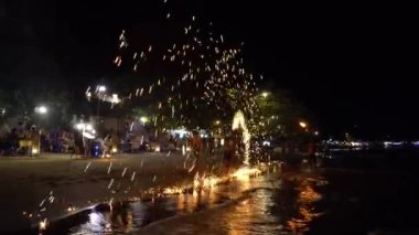 Tayland 'ın Chang Adası sahilinde yangın gösterisi. Yarı çıplak adamlar yangın çubuklarıyla hokkabazlık yapar. Kıvılcımlar farklı yönlere uçar. Denizden gelen dalgalar kıyıya vuruyor. İnsanlar izliyor ve hayran..