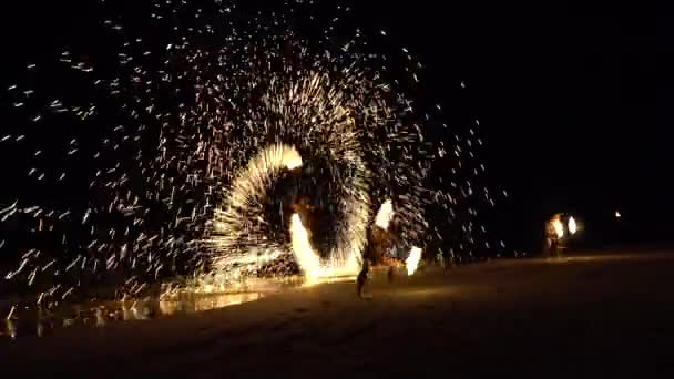 해변에서의 화재쇼 반나체 남자들이 불막대기를 저글링하고 불꽃들은 방향으로 다닙니다 바다로부터의 — 비디오