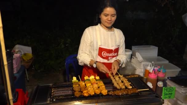 アジアの食べ物と一緒に街を歩く バラエティに富んだ アジア人はパンケーキ ケバブ トウモロコシ ジュース シェイクを準備します 彼らは違う果物を売っている 料理をしながら笑顔と踊ります タイ料理 — ストック動画