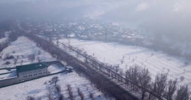 Bir kamyoncu sis içindeki arabalarla otoyolda bir yük taşıyor. Yukarıdan manzara. Sis küçük kasabayı kapladı, kış mevsimi, bazen güneş ışınları yarıp geçti. Kazakistan, Talgar.