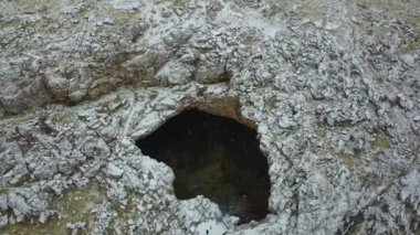 Beyaz caminin kutsal mağarası. Kendi ekolojik iklimi olan büyük bir mağara. Yüzeyde kar yağıyor ve büyük bir tünel deliği görünüyor. Mağaranın içinde ağaçlar ve ısı var. Kuşlar uçar.