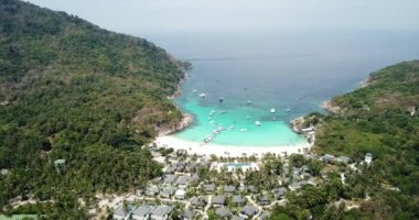 Turkuaz su rengi ve beyaz kum. İnsansız hava aracından, havadan görüntü. Suyun mavi ile koyu mavinin gradyanı. Phuket 'teki Racha adasının yeşil palmiye ağaçları ve tarlaları. Cennetlik kumsal. Tayland