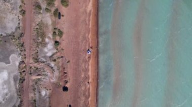 Mavi renkli ve kumlu dalgalı bir sahil. Tatil yapan insanların, çadırların ve arabaların görüntüsü. Balkhash Gölü 'nün kumları. Mavi gökyüzü. Çalılıklar ve birkaç ağaç yetişiyor. Deniz kenarında aile tatili