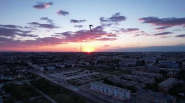 Küçük bir kasabanın üzerinde pembe gün batımı. İHA 'nın üst görüntüsü. Kırlangıç sürüsü uçar. Güneş ufuktan batıyor. Evlerin arka planında mavi-mor bulutlar, bir fabrika ve bir televizyon kulesi. Arabalar sürer, insanlar dinlenir.