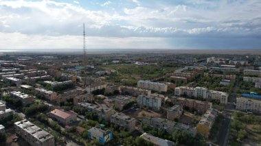 Yağmurdan sonra küçük ıslak bir kasaba. Şehrin üzerinde büyük bulutlar. Yağmur uzaklıktan görülebilir. Yerlerde mavi gökyüzü. Düşük evler, yeşil parklar ve yollar. Televizyon kulesi var. Balkhash şehri, Kazakistan
