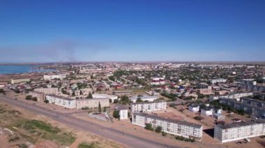 The small town of Balkhash is a view from a drone. A city in the middle of the steppe on the shore of Lake Balkhash. The metallurgical plant is smoking. Bad ecology. Low monotonous houses. Cars drive