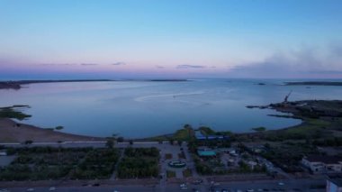 The embankment of the city of Balkhash. A ship is sailing on the lake. Dark green water, calm. Swifts fly. Bertys Bay. People walk along the beach and alleys. Blue clouds are visible in the distance