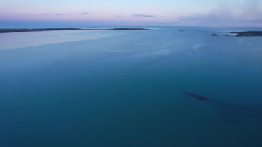 The embankment of the city of Balkhash. A ship is sailing on the lake. Dark green water, calm. Visible streaks of waves from the motor. Bertys Bay. People walk along the beach and alleys. Kazakhstan