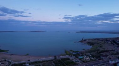 The embankment of the city of Balkhash. A ship is sailing on the lake. Dark green water, calm. Swifts fly. Bertys Bay. People walk along the beach and alleys. Blue clouds are visible in the distance