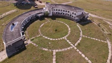An abandoned building with a beautiful pattern of paths. The Assy-Turgen Observatory. The paths are laid out in the form of a telescope. Green grass grows, and purple bushes grow on the roof. Drone