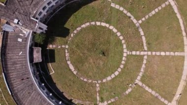 An abandoned building with a beautiful pattern of paths. The Assy-Turgen Observatory. The paths are laid out in the form of a telescope. Green grass grows, and purple bushes grow on the roof. Drone
