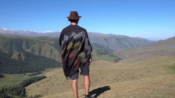 Guy Hat Poncho Standing Edge Hill Looks Distance Blue Sky — Stock video