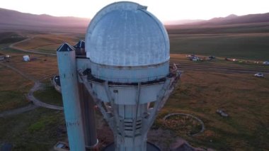 Bright dawn over the Assy-Turgen Observatory in the mountains. Aerial view from the drone of the camp of tents, cars and waking tourists. There is an old abandoned building. Kazakhstan, Almaty