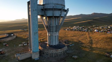 Bright dawn over the Assy-Turgen Observatory in the mountains. Aerial view from the drone of the camp of tents, cars and waking tourists. There is an old abandoned building. Kazakhstan, Almaty