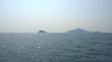Tayland 'da gemiyle seyahat et. Açık okyanus manzarası, yeşil adalar ve sisli gri gökyüzü. Dalgalı yeşil su. Adalar arasında yelken açmak. Farklı taraflardan gemi: kıç, yay, halat, çapa.