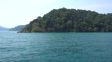 Tayland 'da gemiyle seyahat et. Açık okyanus manzarası, yeşil adalar ve sisli gri gökyüzü. Dalgalı yeşil su. Adalar arasında yelken açmak. Farklı taraflardan gemi: kıç, yay, halat, çapa.