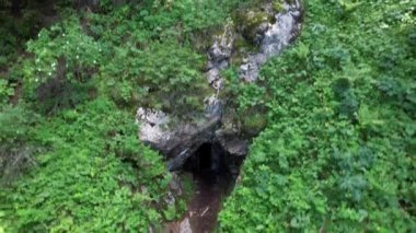 Mağaranın gizli girişi yeşil çimenlerin ve çalıların arasında. Dağlık arazi. Yol eski kapısı olan bir mağaraya çıkıyor. Dik uçurumlar. Kozalaklı orman. Bir eğrelti otu büyüyor. Kazakistan Dağları