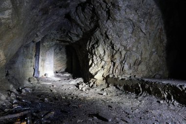 Dağlarda karanlık, yapay bir mağara. Fenerin ışığı kayaların üzerine düşüyor, orada kapı şeklinde geçitler var. Her şey ıslak. Eski dallar ve tuğlalar var..
