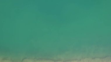 Bir dağ gölünün sularının zümrüt rengi. Dağların yansıması olan yeşil bir dağ gölü üzerindeki bir dronun üst görüntüsü. Pürüzsüz şeffaf su. Yakınlarda büyük taşlar var. Kuru ot