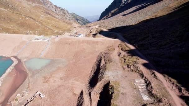 青い水とダムと山の人工湖 水のターコイズブルーの表面は山々を反映しています 近くに泥だらけの水のある小さな湖があります 山の中の護岸ダム — ストック動画