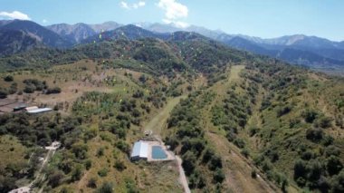 Dağların arka planındaki renkli parlak toplar gökyüzüne doğru uçuyor. Sarı, yeşil, kırmızı, mavi top daha da yükselecek. Yeşil vadi, karlı tepeler. Mavi gökyüzünde beyaz bulutlar var. Tatil